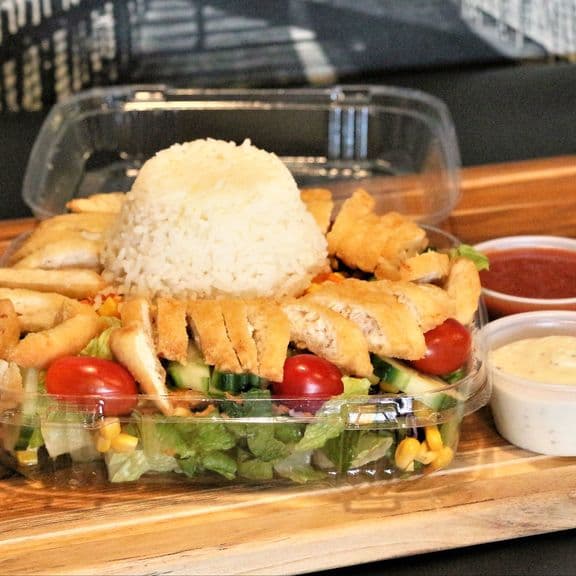 Rice Bowl Salad - Fresh lettuce, shredded carrots, sweet corn, cucumbers, tomato, and red cabbage topped with crispy chicken and seasoned rice. Served with ranch and hot sauce.