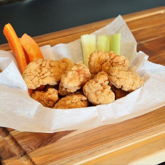 Boneless Wings - Ten pieces of premium, hand-breaded boneless chicken wings, fried to golden perfection. Each piece features tender chicken in a crispy coating, accompanied by our signature sauce.