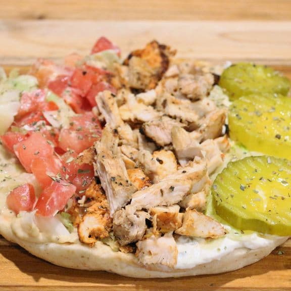 Chicken Pita Wrap - Special house marinated chicken, fresh lettuce, tomato, pickles, hummus and tzatziki sauce, wrapped in warm pita bread.